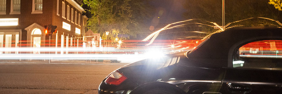 image of a car at night with blurred lights from traffic behind it